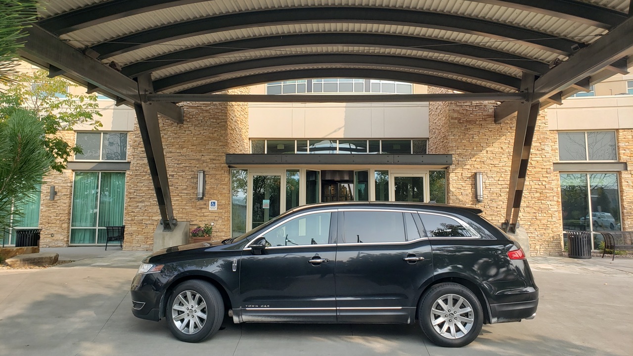 Private black sedan by the entrance of The Renaissance Hotel in Broomfield Colorado waiting for a passenger
